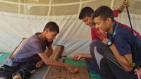 Abdallah and his older brother play draughts in their tent.